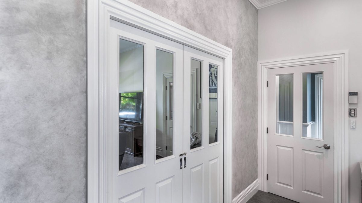 An interior with a mottled grey feature wall finish, white glazed double doors and a white panelled door