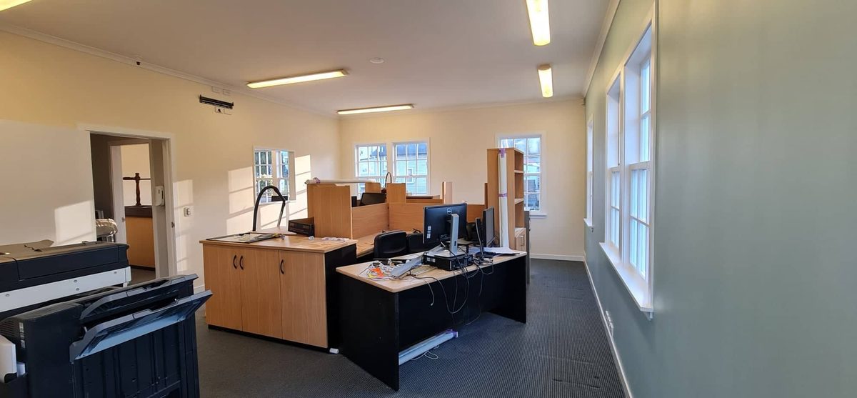 An office with cream walls, white sash windows and wooden desks with computers